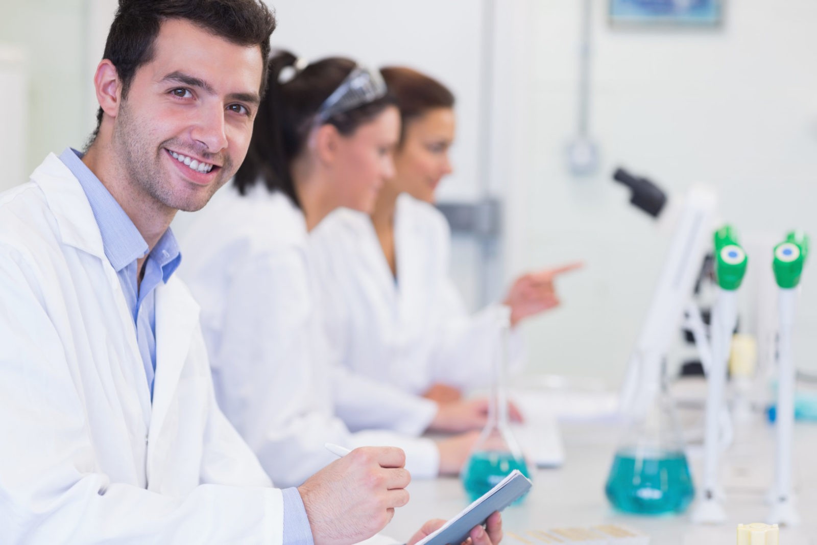Scientists at lab bench with male scientist smiling